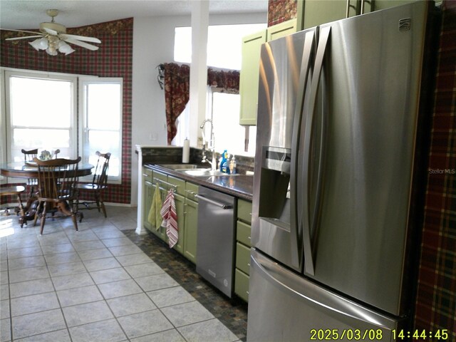 kitchen featuring a sink, dark countertops, stainless steel appliances, green cabinets, and light tile patterned floors