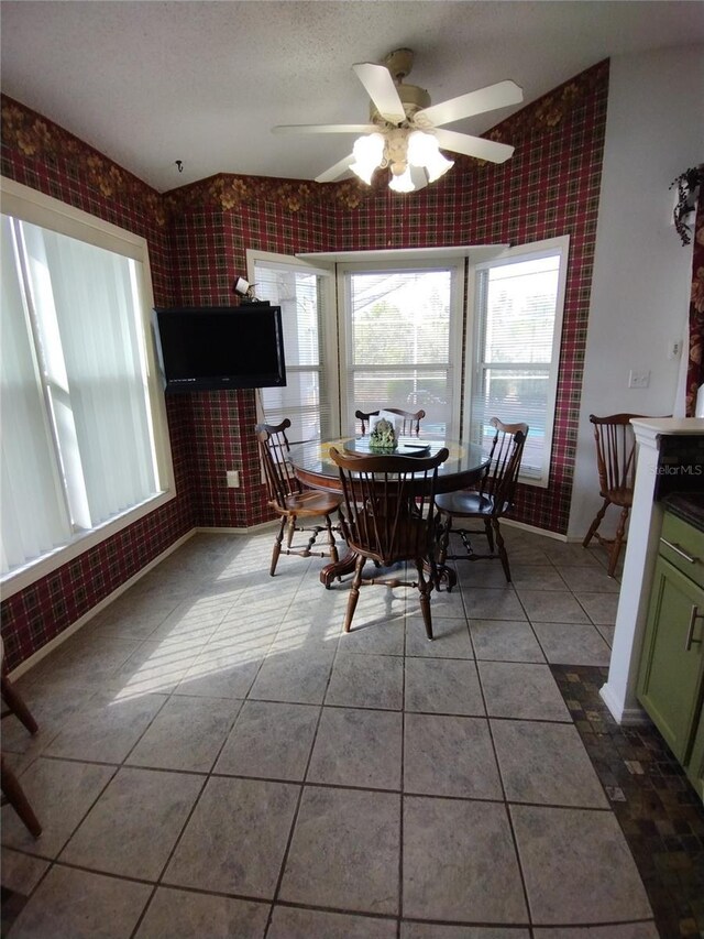 dining space with tile patterned floors, a ceiling fan, brick wall, and a textured ceiling