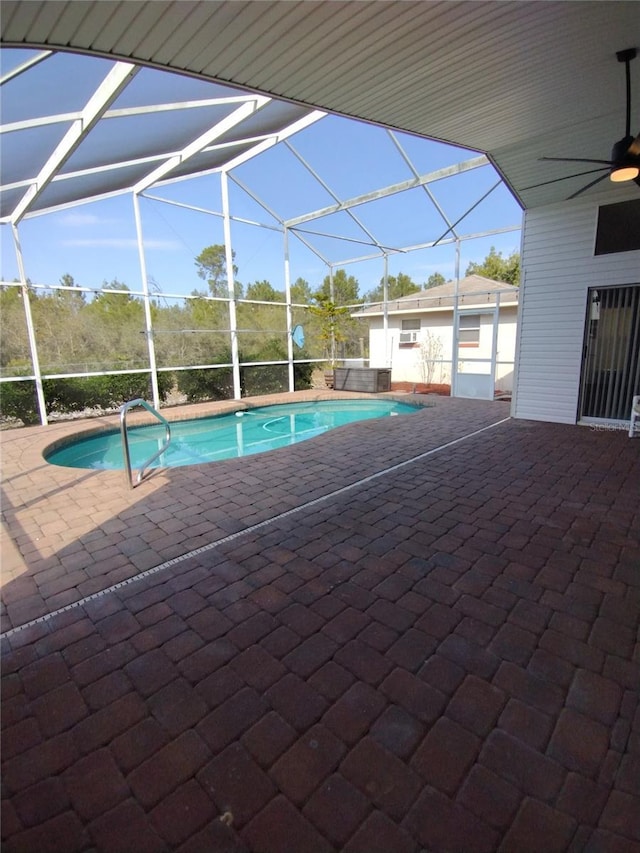 outdoor pool featuring glass enclosure, a patio, and a ceiling fan