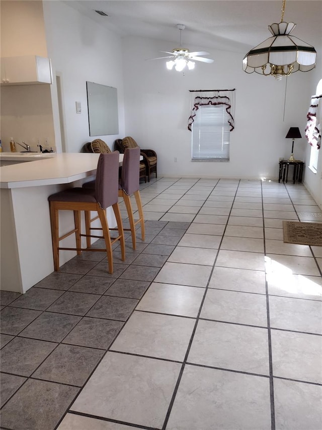 unfurnished dining area featuring tile patterned floors, lofted ceiling, ceiling fan, and a sink