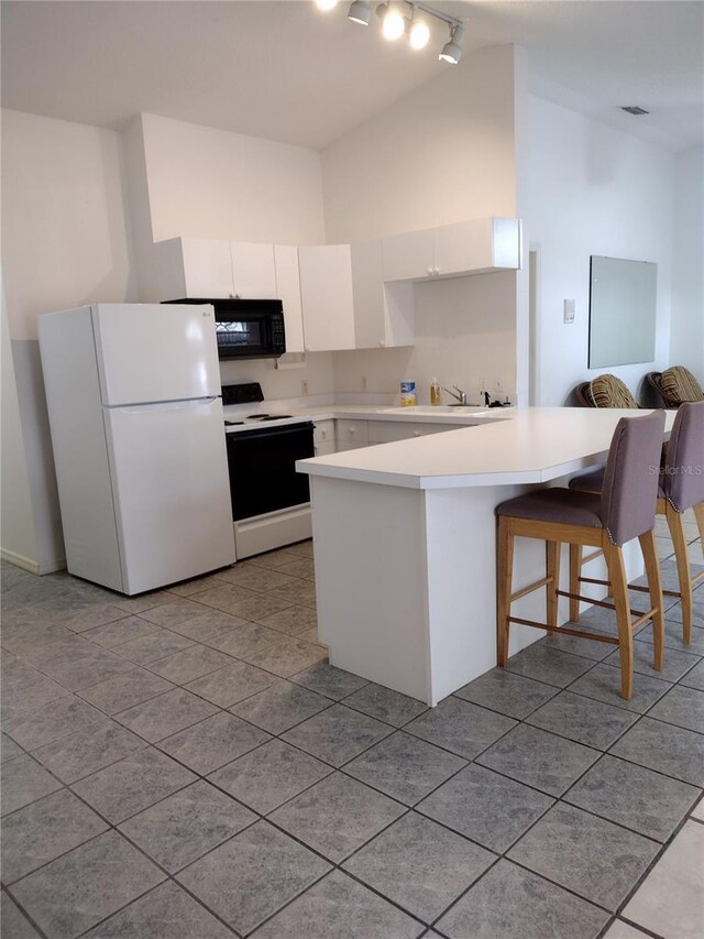 kitchen with freestanding refrigerator, light countertops, electric stove, black microwave, and white cabinetry