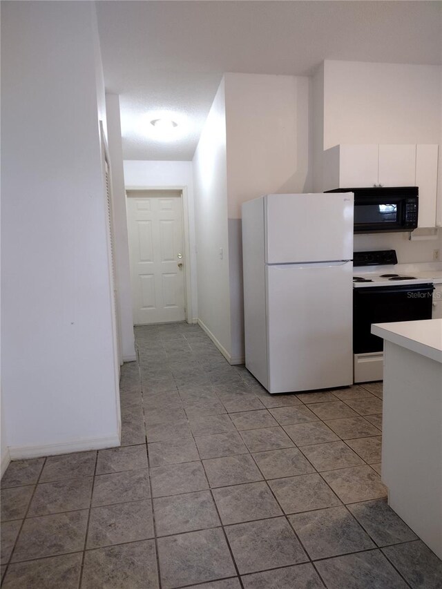 kitchen featuring electric range, white cabinetry, freestanding refrigerator, black microwave, and light countertops