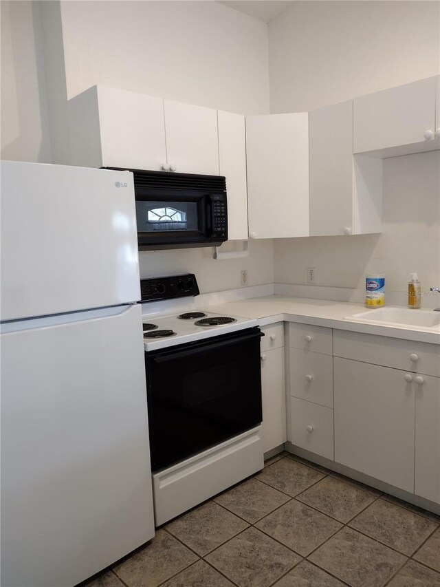 kitchen with a sink, white cabinetry, white appliances, tile patterned flooring, and light countertops