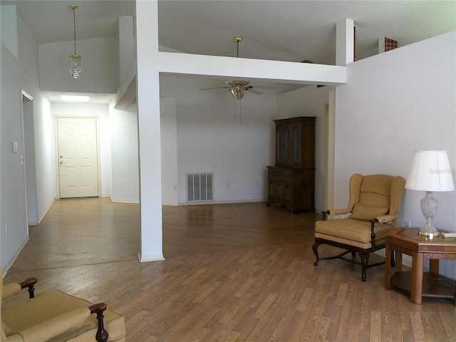sitting room with wood finished floors, a ceiling fan, visible vents, and high vaulted ceiling