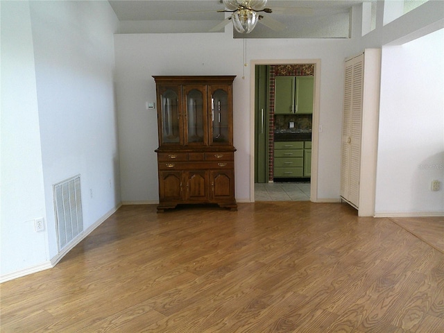empty room with baseboards, a ceiling fan, visible vents, and light wood-style flooring