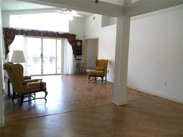 sitting room with ceiling fan, a high ceiling, wood finished floors, and baseboards
