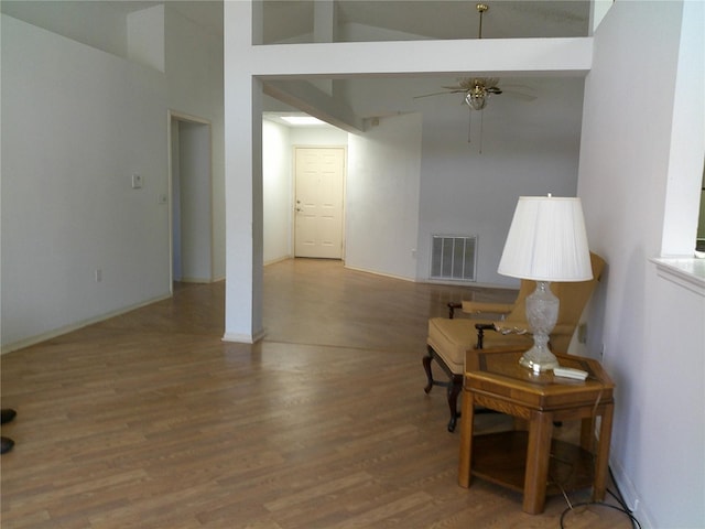 interior space featuring wood finished floors, visible vents, baseboards, high vaulted ceiling, and ceiling fan