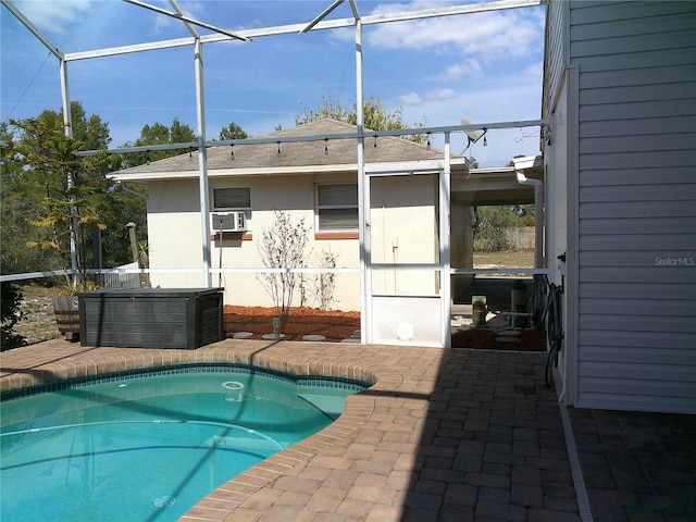 outdoor pool featuring a lanai, a hot tub, a patio area, and cooling unit