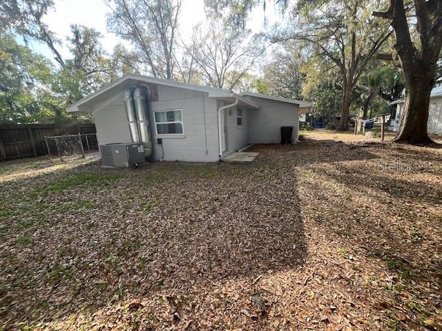 rear view of property featuring central AC unit and fence