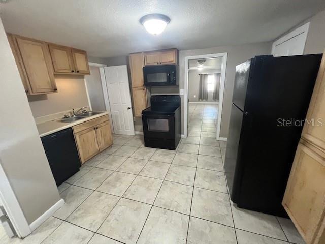 kitchen with black appliances, a sink, light tile patterned flooring, light countertops, and baseboards