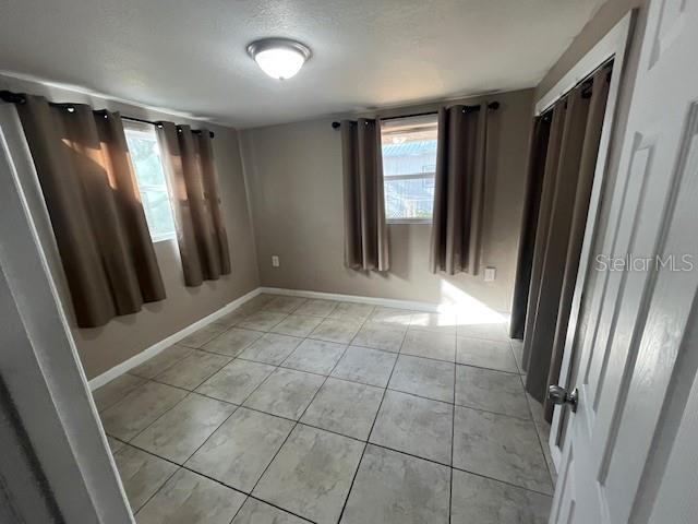 unfurnished room featuring baseboards and light tile patterned flooring