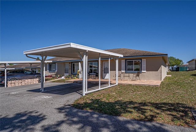 back of property featuring a yard, covered parking, and stucco siding