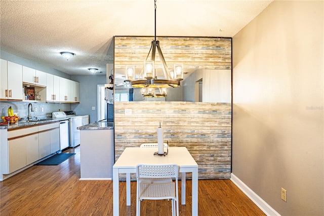 dining area with a chandelier, baseboards, a textured ceiling, and dark wood-style floors