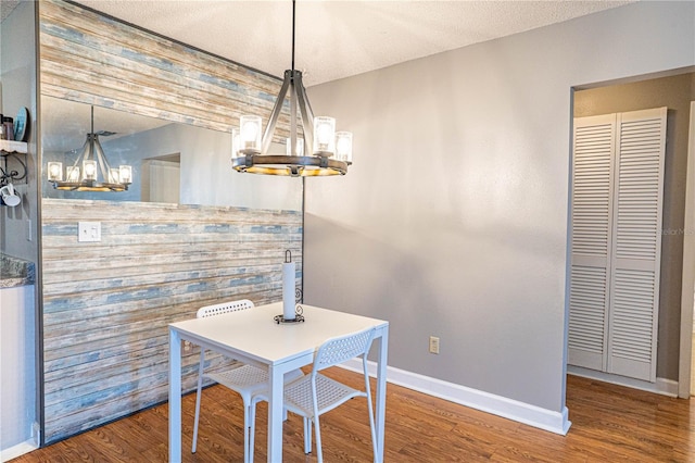 dining area with baseboards, wood finished floors, a textured ceiling, and a chandelier