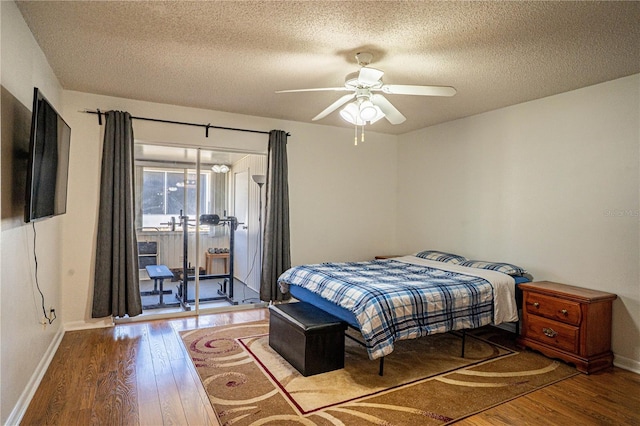 bedroom with access to exterior, a textured ceiling, baseboards, and wood-type flooring