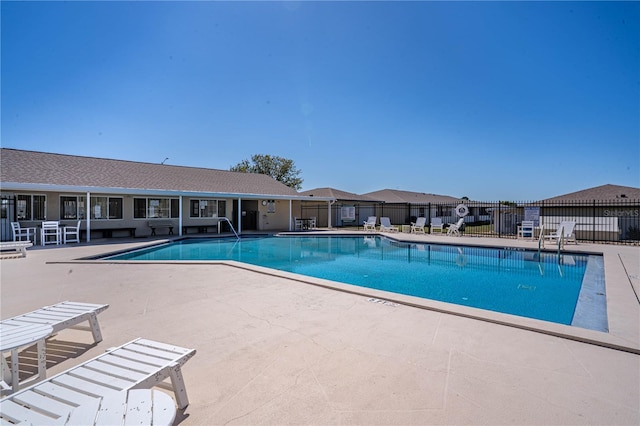 community pool with a patio area and fence