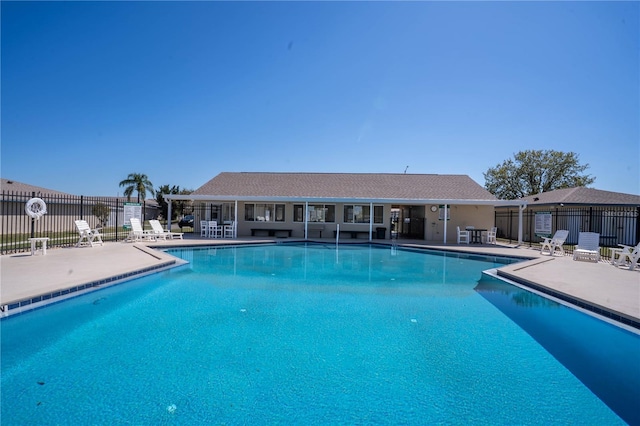 community pool with a patio area and fence