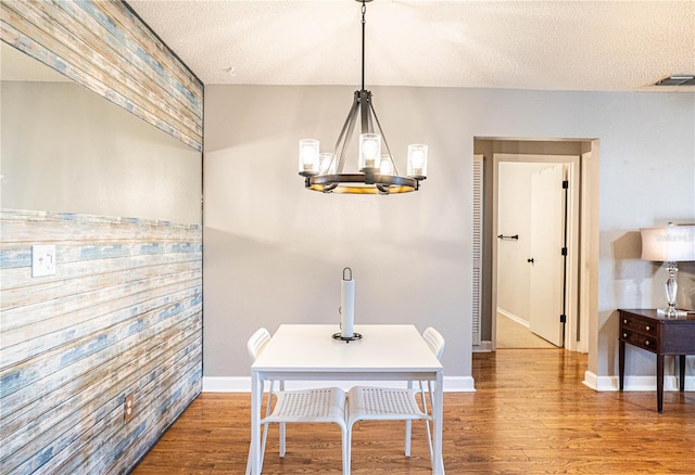 dining room with a textured ceiling, wood finished floors, visible vents, and a chandelier