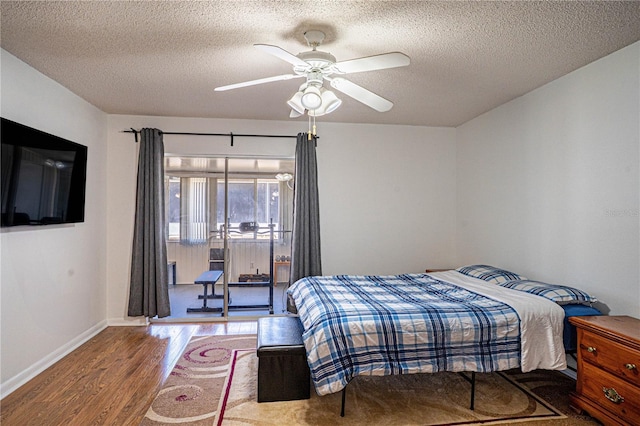 bedroom featuring baseboards, a textured ceiling, and wood finished floors