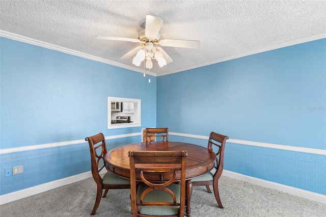 dining area featuring a textured ceiling, ceiling fan, wainscoting, and wallpapered walls