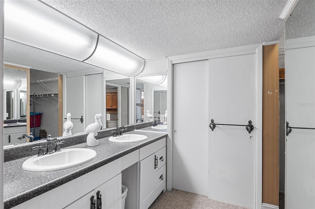 bathroom featuring double vanity, a textured ceiling, and a sink