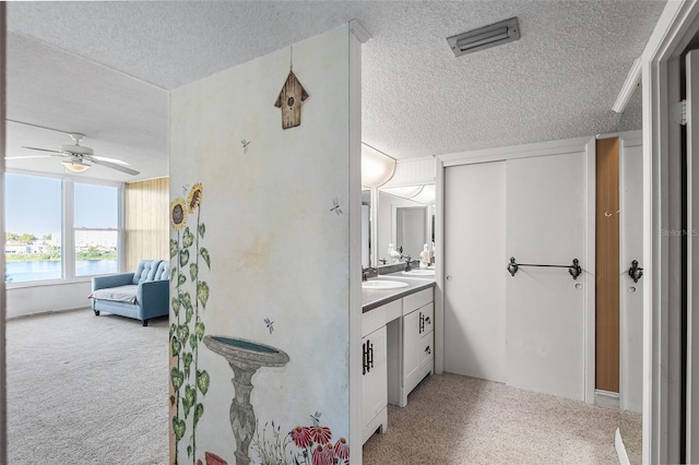 ensuite bathroom with visible vents, a textured ceiling, connected bathroom, and vanity