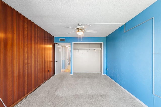 unfurnished bedroom featuring visible vents, carpet flooring, a closet, a textured ceiling, and a ceiling fan