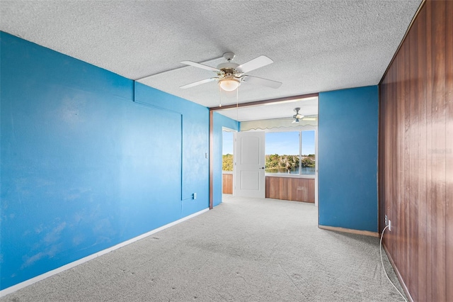 unfurnished room with a textured ceiling, baseboards, carpet floors, and ceiling fan