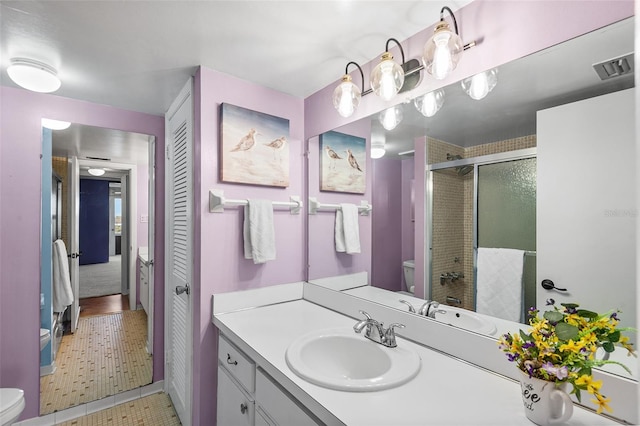 bathroom with visible vents, toilet, a stall shower, and vanity