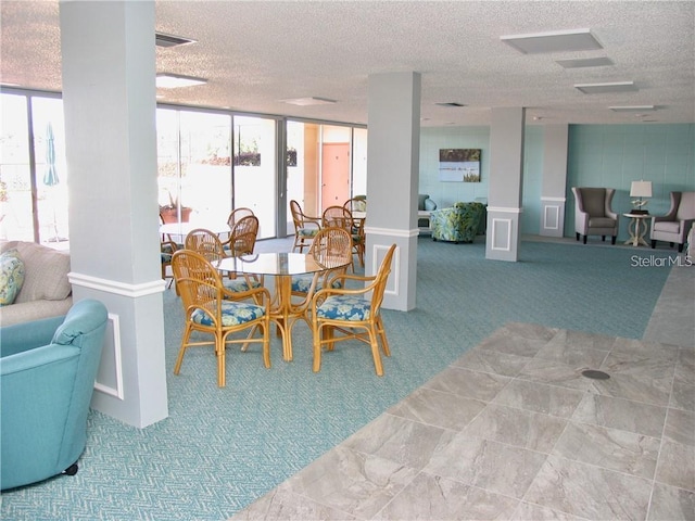 carpeted dining space featuring plenty of natural light, a textured ceiling, and decorative columns