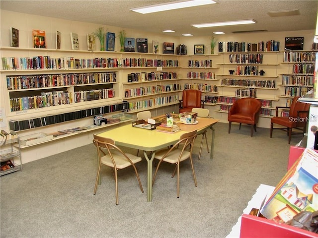 living area featuring carpet floors, a textured ceiling, and wall of books