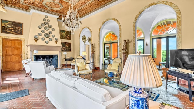 living area featuring an inviting chandelier, a fireplace, crown molding, and a towering ceiling