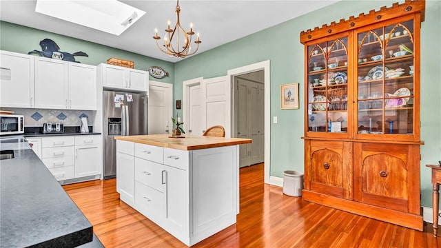 kitchen featuring light wood-type flooring, butcher block countertops, stainless steel refrigerator with ice dispenser, tasteful backsplash, and white cabinetry