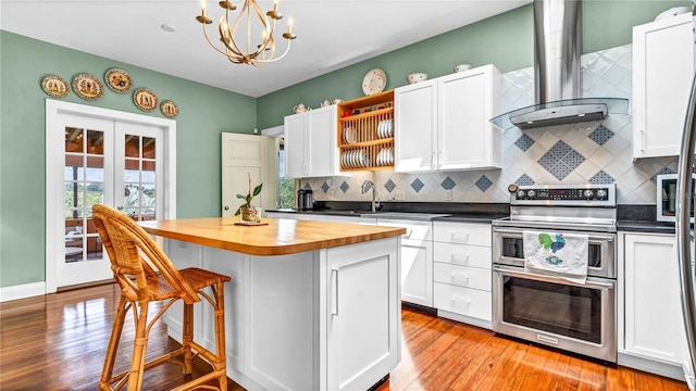 kitchen featuring butcher block countertops, double oven range, a kitchen breakfast bar, wall chimney exhaust hood, and open shelves