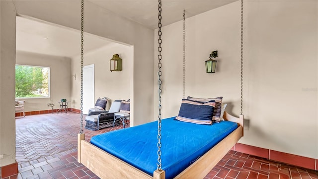 bedroom featuring brick floor and baseboards