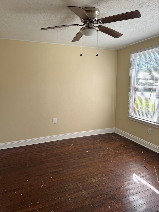 empty room with baseboards, a textured ceiling, and dark wood finished floors