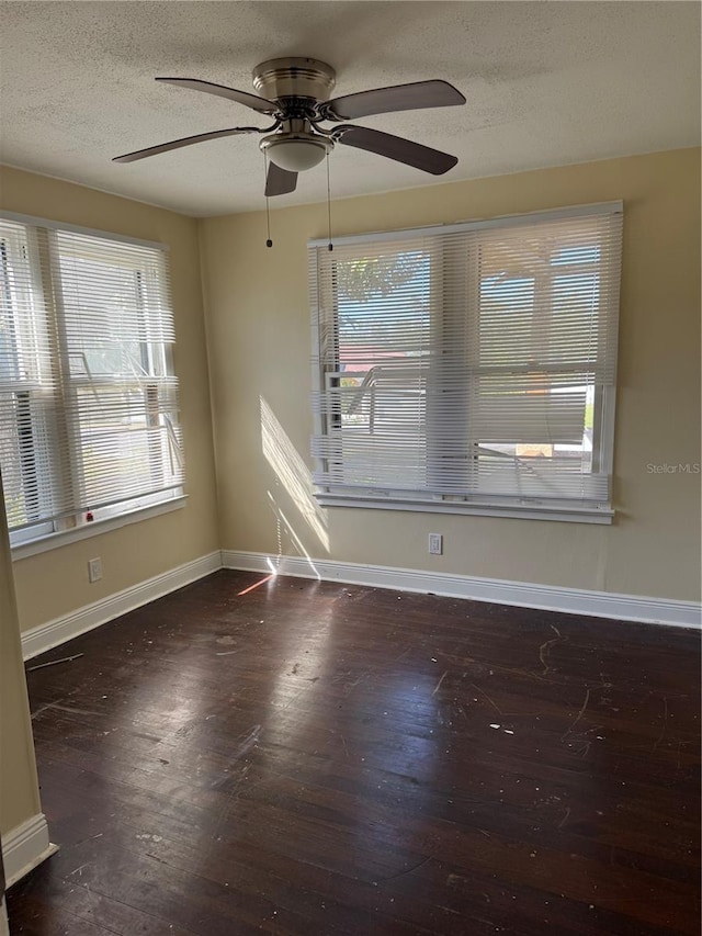 spare room featuring wood finished floors, baseboards, and a textured ceiling