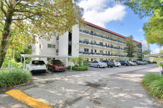 view of building exterior with covered and uncovered parking