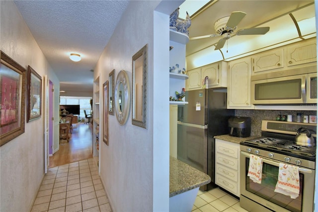 kitchen featuring light tile patterned flooring, a textured ceiling, stainless steel appliances, and ceiling fan