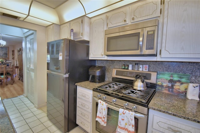 kitchen with stone countertops, backsplash, appliances with stainless steel finishes, and light tile patterned flooring