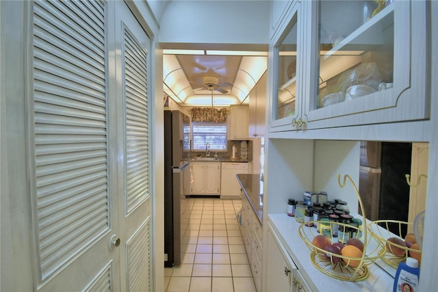 kitchen featuring a sink, white dishwasher, light tile patterned floors, decorative backsplash, and a raised ceiling