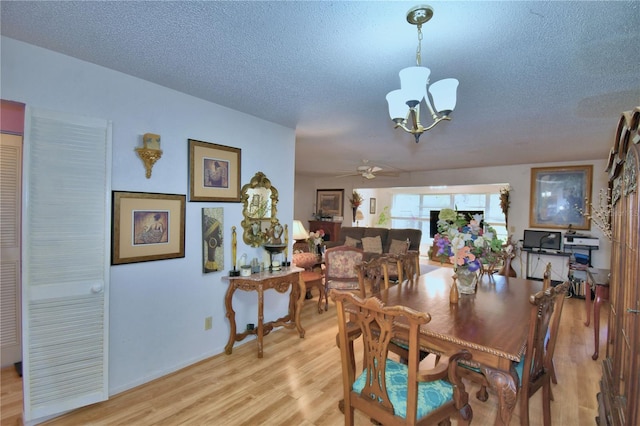 dining space with light wood-style flooring, ceiling fan with notable chandelier, baseboards, and a textured ceiling