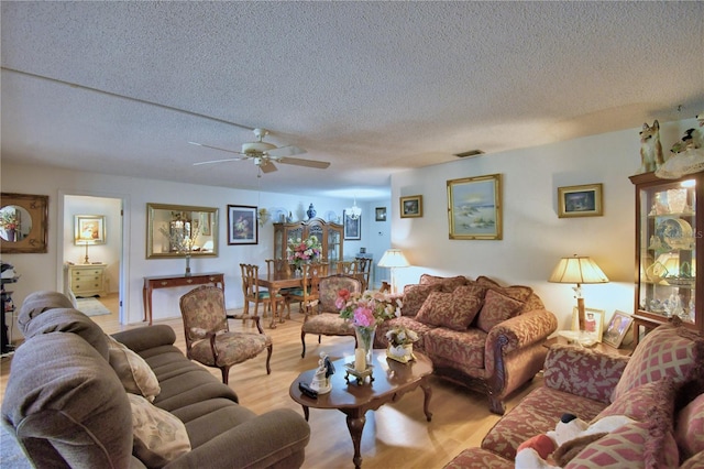 living area with visible vents, a textured ceiling, ceiling fan, and light wood finished floors