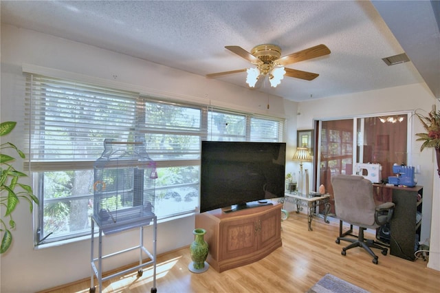 home office featuring light wood-style flooring, a textured ceiling, and ceiling fan