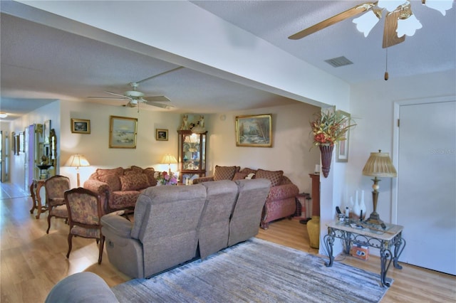 living room with ceiling fan, visible vents, and light wood-type flooring