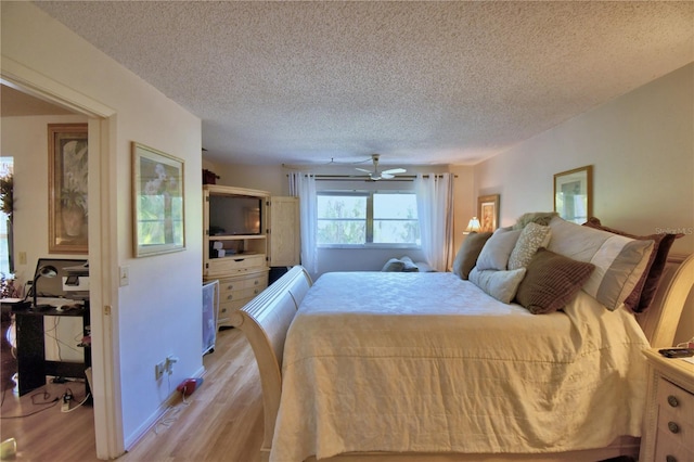 bedroom featuring light wood-style floors, ceiling fan, and a textured ceiling