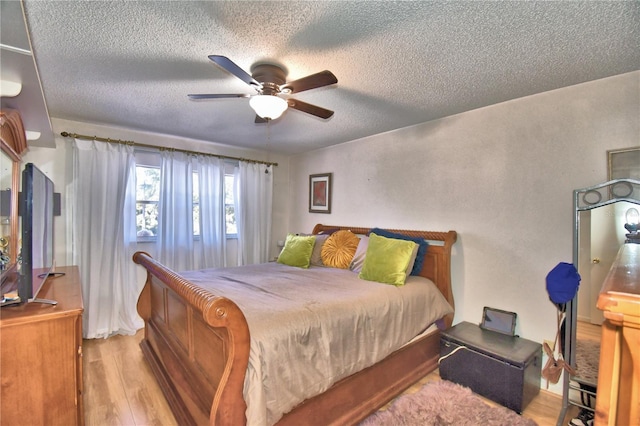 bedroom featuring a ceiling fan, wood finished floors, and a textured ceiling