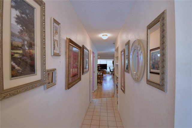 corridor with light tile patterned floors and a textured ceiling