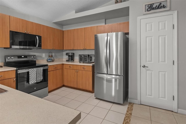 kitchen with light tile patterned flooring, stainless steel appliances, light countertops, and lofted ceiling