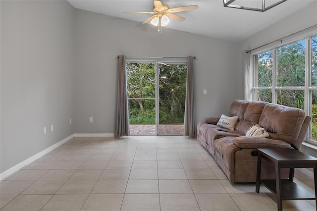 living area featuring lofted ceiling, light tile patterned flooring, a ceiling fan, and a wealth of natural light